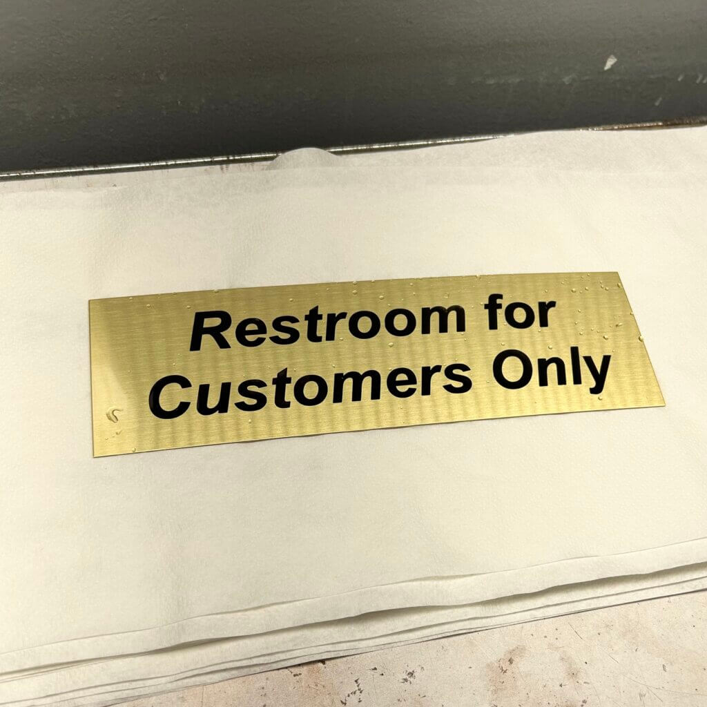 An Oxidized Custom Engraved Brass Plate Saying Restroom for Customers Only