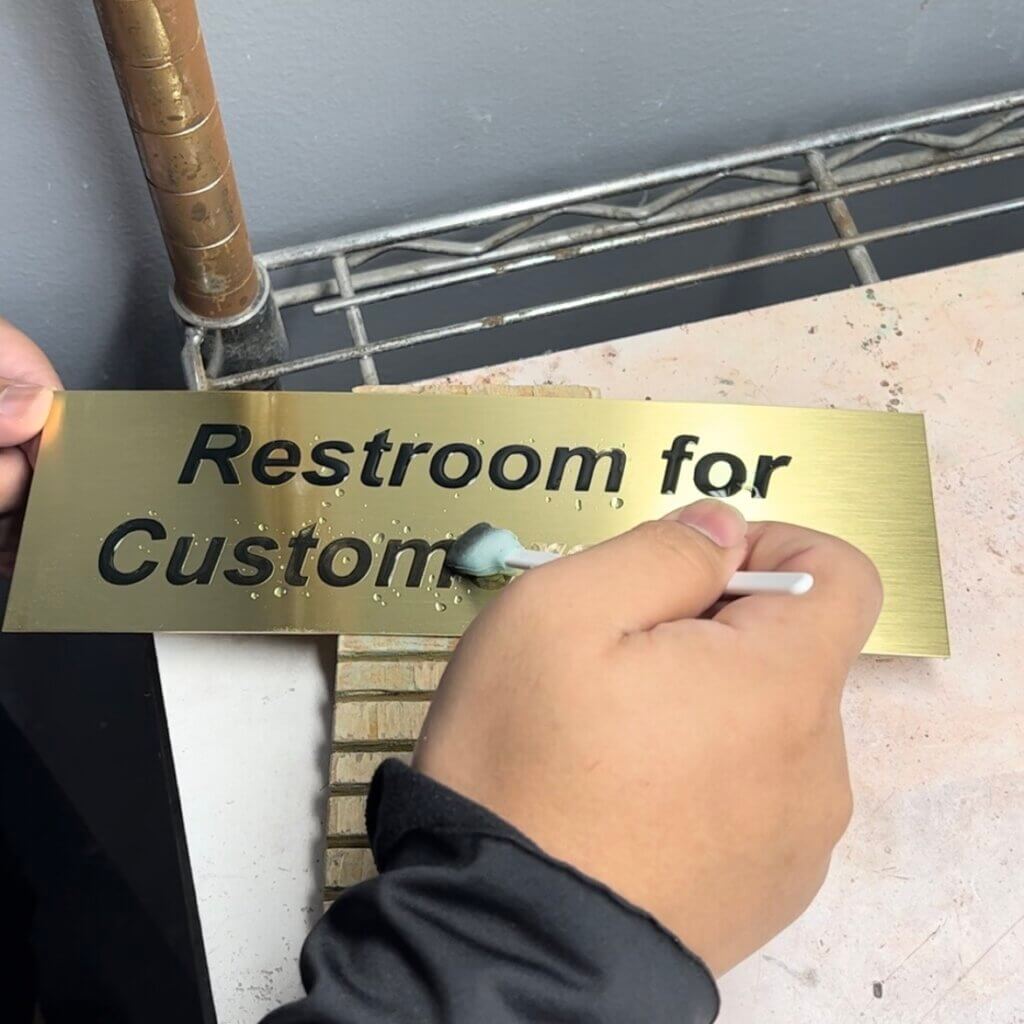 An Oxidization Solution Being Applied to the Engraved Areas of the Brass Plate