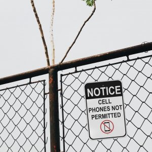 No Cell Phones Sign on a Chain Link Fence
