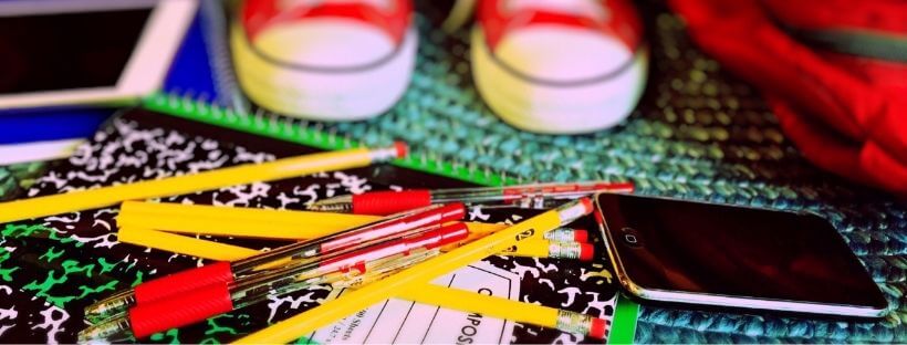 Pencils, Pens, and a Cell Phone on a Composition Notebook